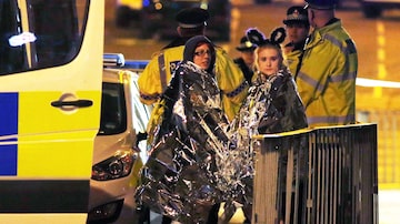 Mulheres se aquecem nas imediações do Manchester Arena após explosão. Foto: REUTERS/Andrew Yates
