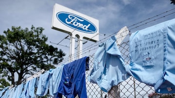 Operários penduram uniformes nas grades da Ford com nomes da família. Foto: Roosevelt Cassio/Reuters