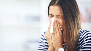 Its allergy season again. Shot of a young woman with allergies sneezing into a tissue at home. Foto: Yuri Arcurs/peopleimages.com/Adobe Stock