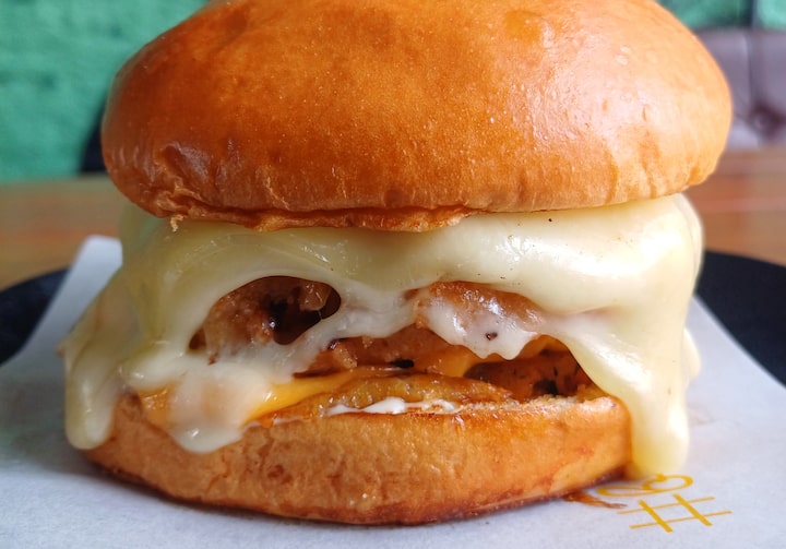 Hambúrguer com quatro queijos no pão brioche.