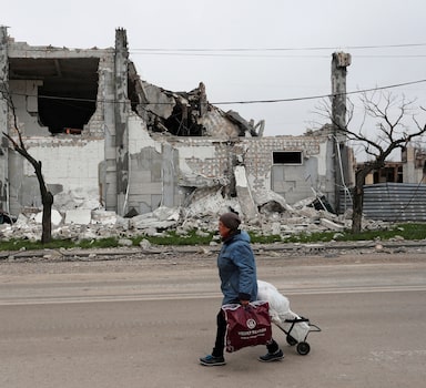 Mulher caminha pelas ruas destruídas de Mariupol