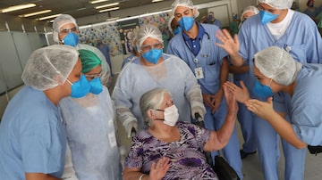 Ao receber alta, a aposentada Guiomar Sargo de Lima, de 83 anos, é saudada por profissionais de saúde do hospital de campanha do Anhembi. Foto: Daniel Teixeira/Estadão