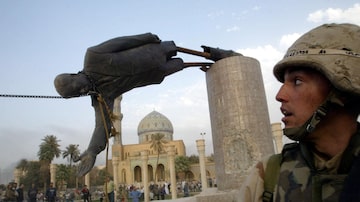 FILE PHOTO: A U.S. soldier watches as a statue of Iraq's President Saddam Hussein falls in central Baghdad, Iraq April 9, 2003. U.S. troops pulled down a 20-foot (six metre) high statue of President Saddam Hussein in central Baghdad on Wednesday and Iraqis danced on it in contempt for the man who ruled them with an iron grip for 24 years. In scenes reminiscent of the fall of the Berlin Wall in 1989, Iraqis earlier took a sledgehammer to the marble plinth under the statue of Saddam. Youths had placed a noose around the statue's neck and attached the rope to a U.S. armoured recovery vehicle. Pictures of the month April 2003  REUTERS/Goran Tomasevic/File Photo. Foto: Goran Tomasevic/Reuters