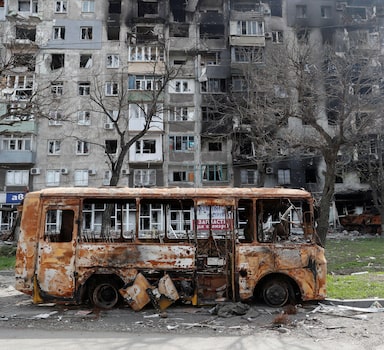A burnt out bus is seen in front of a residential building damaged during Ukraine-Russia conflict in the southern port city of Mariupol, Ukraine April 19, 2022. REUTERS/Alexander Ermochenko