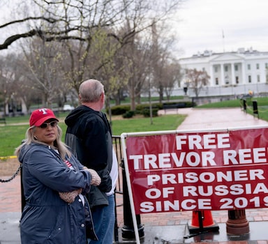 (FILES) In this file photo taken on March 30, 2022, Paula and Joey Reed, parents of Trevor Reed, stand next to a banner reading “Free Trevor Reed” in Lafayette Square near the White House in Washington, DC. - Russia and the US announced a prisoner swap on April 27, 2022, despite fierce tensions over Ukraine, with Moscow handing over ex-Marine, Trevor Reed, in exchange for a Russian pilot convicted of drug smuggling. Reed, a 30-year-old from Texas who was jailed in Russia in 2020, was exchanged for Konstantin Yaroshenko, 53, who had been serving a 20-year US prison sentence since 2011. (Photo by Stefani Reynolds / AFP)