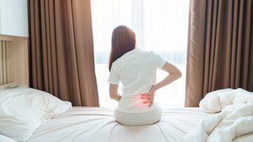woman having back body ache during sitting on bed at home. adult female with muscle pain after Waking up due to Piriformis Syndrome, Low Back Pain and Spinal Compression. Health medical concept. Foto: Jo Panuwat D/Adobe Stock