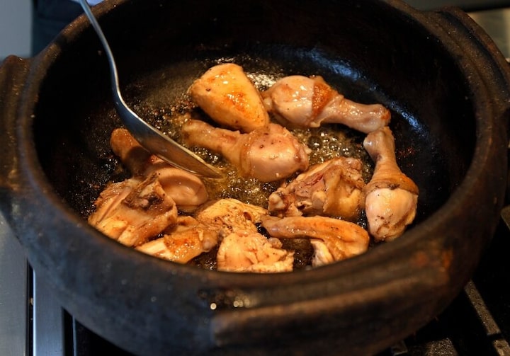 Panela com frangos sendo preparado para o prato chamado "galinhada".
