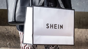 A woman holds a Shein shopping bag stand outside the first permanent showroom of Chinese online fast fashion giant Shein on the opening day of the shop in Tokyo on November 13, 2022. (Photo by Yuichi YAMAZAKI / AFP). Foto: Yuichi Yamazaki/AFP