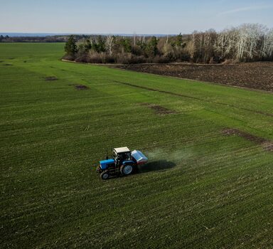 FILE PHOTO: An aerial view shows a tractor spreading fertiliser on a wheat field near the village of Yakovlivka after it was hit by an aerial bombardment outside Kharkiv, as Russia's attack on Ukraine continues, April 5, 2022. Picture taken with a drone. REUTERS/Thomas Peter/File Photo