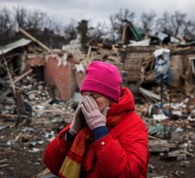 Mulher se emociona diante de casas destruídas por bombardeio em Irpin, na Ucrânia