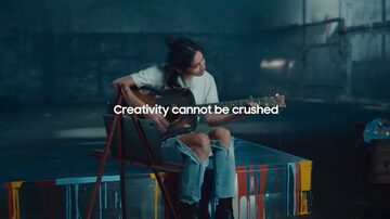 Uma mulher segurando um violão, sentada sobre uma máquina de prensa e a frase “Criatividade não pode ser destruída”. Foto: Reprodução/Redes Sociais/Youtube