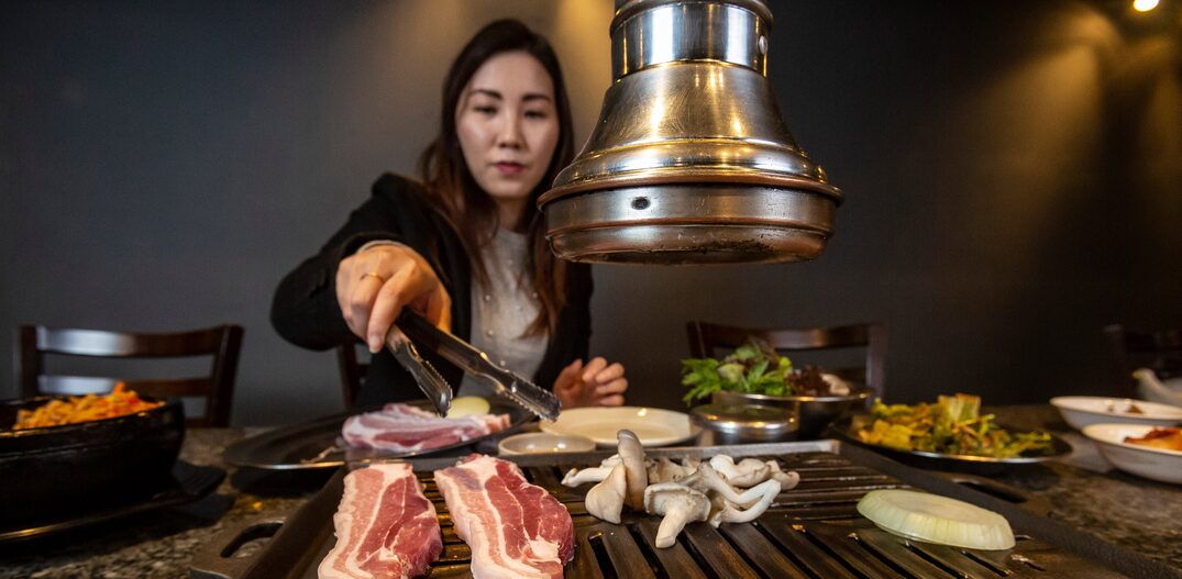 A jornalista coreana Yoo Na Kim mostra como comer o típico churrasco coreano, preparado à mesa,New Shin La Kwan. Foto: Taba Benedicto/Estadão