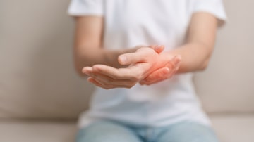 Woman having wrist pain during sitting on sofa at home, muscle ache due to De Quervain s tenosynovitis, ergonomic, Carpal Tunnel Syndrome or Office syndrome concept. Foto:  Jo Panuwat D/Adobe Stock 