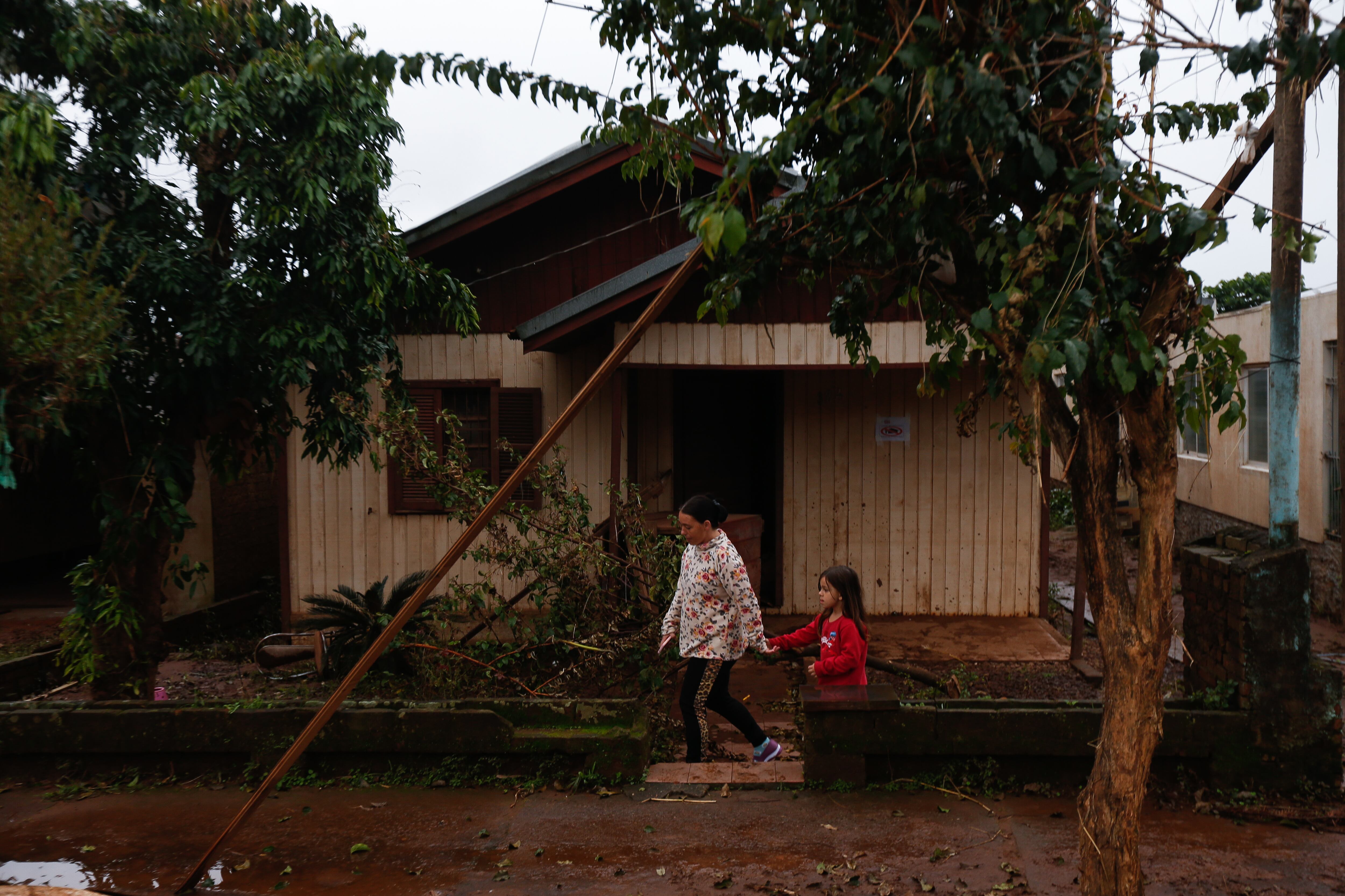 Darlise caminha com a filha Isadora em meio aos efeitos das enchentes que atingiram Roca Sales, no interior do Rio Grande do Sul