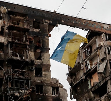 FILE PHOTO: A view shows a torn flag of Ukraine hung on a wire in front an apartment building destroyed during Ukraine-Russia conflict in the southern port city of Mariupol, Ukraine April 14, 2022. REUTERS/Alexander Ermochenko/File Photo
