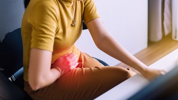 Woman having painful stomach ache during working at home. Foto: gballgiggs/Adobe Stock