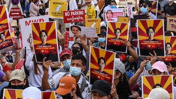 Cartazes em apoio à líder civil deposta de Mianmar, Aung San Suu Kyi, são erguidos por manifestantes em Yangon. Foto: Sai Aung Main/ AFP