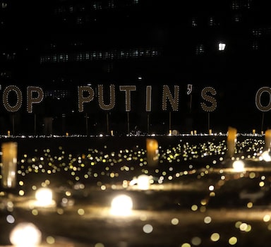 A signs reads "Stop Putin's oil" during a vigil for Ukraine near the European Union (EU) headquarters in Brussels, on March 22, 2022. - Demonstrators call on EU leaders to impose a full ban on Russian fuels. (Photo by Valeria Mongelli / AFP)
