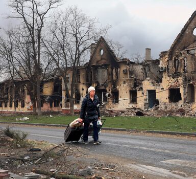 Ucraniana passa por casas destruídas por ataques russos em Mariupol