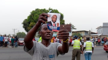 Eleitor de George Weah comemora nas ruas de Monróvia, capital da Libéria, a vitória do ex-jogador de futebol e novo presidente do país. Foto: AFP PHOTO / SEYLLOU