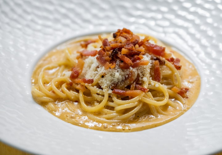 Espaguete à carbonara tradicional em um prato fundo de louça branco.