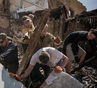 Volunteers on May 3 clear an area of Kharkiv, Ukraine, that was destroyed in a strike. MUST CREDIT: Photo for The Washington Post by Wojciech Grzedzinski