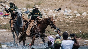 Oficiais montados da Alfândega e Proteção de Fronteiras dos EUA tentam contermigrantes haitianos enquanto eles cruzam o Rio Grande, em Acunã. Foto: AP/Felix Marquez - arquivo