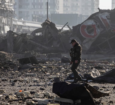 Soldado ucraniano caminha sobre destroços após ataque russo destruir shopping em Kiev, Ucrânia