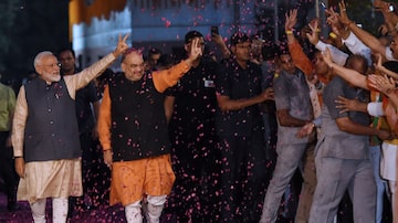 Primeiro-ministro indiano, Narendra Modi (à esquerda), com presidente do BJP, Amit Shah, acena para eleitores após vitória na Índia. Foto: (Photo by Money SHARMA / AFP)