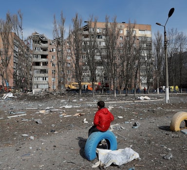 A boy sits in front of a residential building damaged by shelling during Ukraine-Russia conflict in the separatist-controlled city of Donetsk, Ukraine March 30, 2022. REUTERS/Alexander Ermochenko