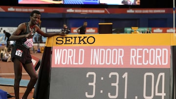 Samuel Tefera ao lado do marcador que mostra seu tempo recorde nos 1500 metros. Foto: David Davies/AP