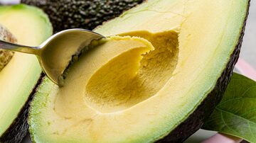 Eating of fresh ripe green organic hass avocado fruit with spoon. Foto: barmalini/Adobe Stock