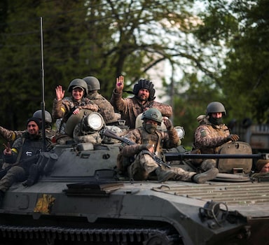 Ukrainian service members wave as they ride on top of an armoured vehicle, amid Russia's attack on Ukraine, in Kharkiv, Ukraine, May 16, 2022. REUTERS/Ricardo Moraes
