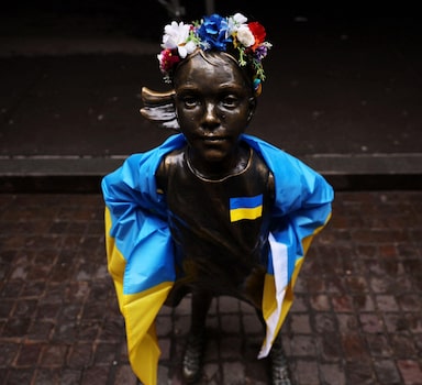 A popular estátua de bronze da "Menina Sem Medo", da artista Kristen Visbal, foi envolta com uma bandeira da Ucrânia nesta quarta-feira após uma manifestação do lado de fora da Bolsa de Valores de Nova York. Foto: Shannon Stapleton/Reuters