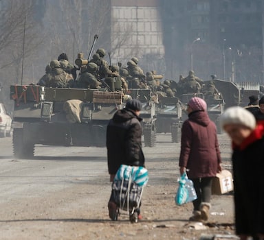 Service members of pro-Russian troops drive armoured vehicles past local residents in the course of Ukraine-Russia conflict in the besieged southern port city of Mariupol, Ukraine March 24, 2022. REUTERS/Alexander Ermochenko