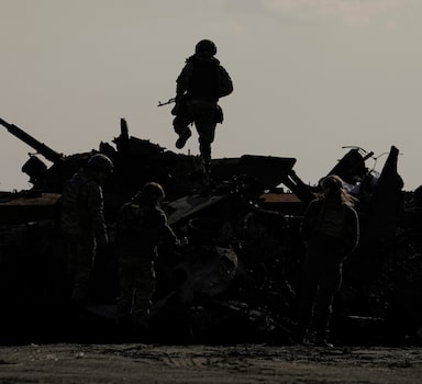 Soldado ucraniano caminha sobre destroços de veículo de combate russo