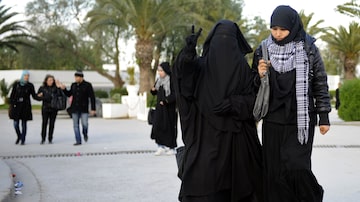 Estudante da Faculdade de Artes e Letras de Manuba, vestindo niqab (E), acena na Tunísia. Foto: Fethi Belaid / AFP