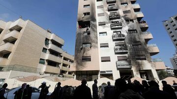 Sírios checam um prédio danificado na capital Damasco após um bombardeio aéreo israelense 
