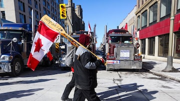 Manifestante com bandeira do Canadá diante de bloqueio de caminhoneiros em Ottawa, em 14 de fevereiro. Foto: Lars Hagberg/Reuters