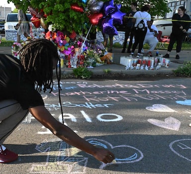 People leave messages at a makeshift memorial near a Tops Grocery store in Buffalo, New York, on May 15, 2022, the day after a gunman shot dead 10 people. - Grieving residents from the US city of Buffalo held vigils Sunday after a white gunman who officials have deemed "pure evil" shot dead 10 people at a grocery store in a racially-motivated rampage (Photo by Usman KHAN / AFP)