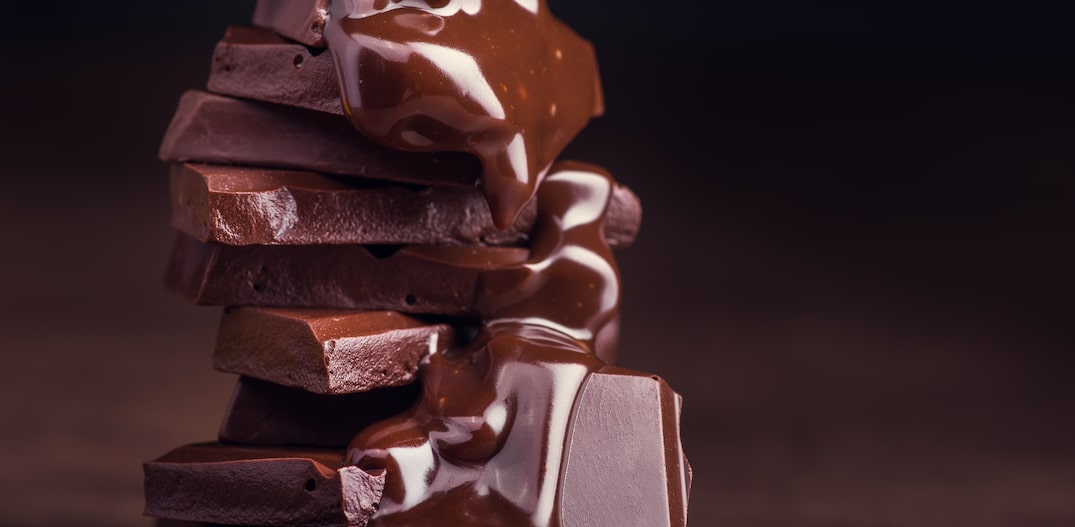 melted chocolate pouring into a piece of chocolate bars with green mint leaf on a table. Foto: DimaSobko | Adobe Stock