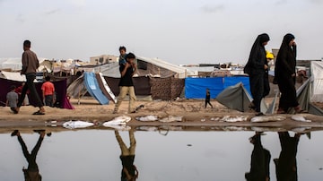 Palestinos caminham ao lado de um vazamento de esgoto perto de tendas de refugiados no campo de Rafah, no sul da Faixa de Gaza: 1,7 milhão de pessoas vivem no local 