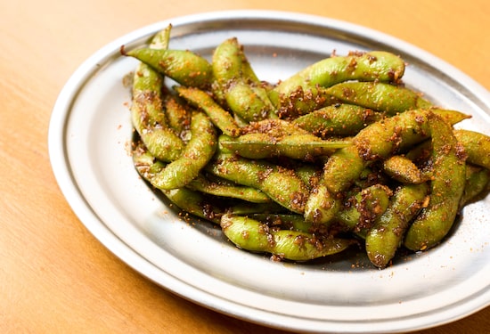 Edamame no prato de inox sobre a mesa de madeira. Foto: Otoshi Izakaya/ Divulgação Edamame no prato de inox sobre a mesa de madeira. Foto: Otoshi Izakaya/ Divulgação