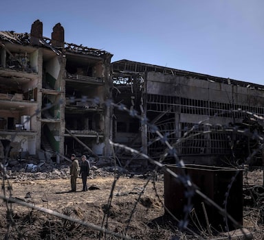TOPSHOT - People stand beside damaged buildings  at the Vizar company military-industrial complex, after the site was hit by overnight Russian strikes, in the town of Vyshneve, southwestern suburbs of Kyiv, on April 15, 2022. - A Ukrainian military factory outside Kyiv that produced missiles allegedly used to hit Russia's Moskva warship was partly destroyed by overnight Russian strikes, an AFP journalist at the scene saw on April 15. A workshop and an administrative building at the Vizar plant were seriously damaged. (Photo by FADEL SENNA / AFP)