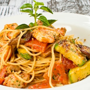 Em um prato fundo de louça branco está o spaguettini com camarão e legumes. Foto: NOU/Divulgação