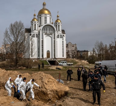 Bodies are exhumed from a communal grave near the Church of St. Andrew in Bucha, Ukraine, April 8, 2022. As the Russian advance on Kyiv stalled, a campaign of terror and revenge against civilians nearby in Bucha began, survivors and investigators say. (Daniel Berehulak/The New York Times)