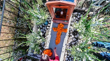Mulher decora sepultura no Panteón La Magdalena, cemitério em San Pedro Cholula, no México. Foto: Pedro Pardo/AFP