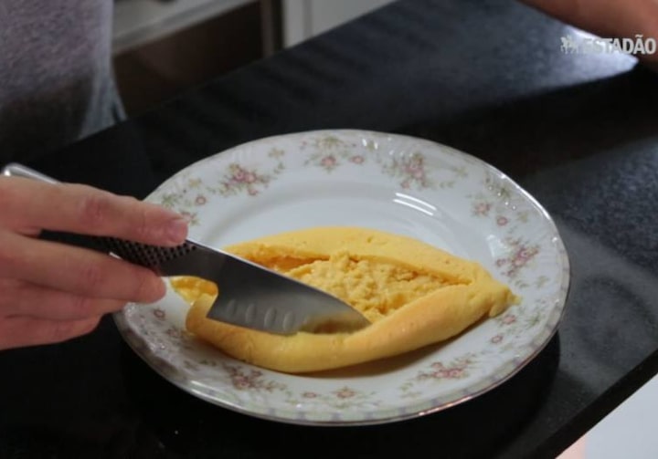 Mão masculina com faca montando o omelete