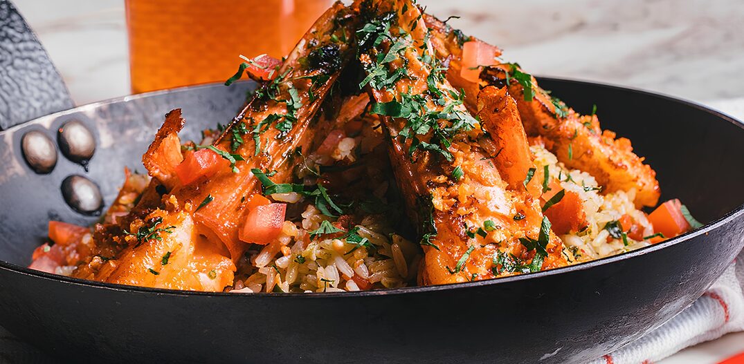 Em uma frigideira preta está o Camarão à provençal com camarões grandes, tomates picados, arroz e salpicado com temperos verdes. Foto: ICI Brasserie/Divulgação