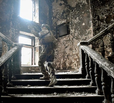 Soldado russo nas escadarias do teatro de Mariupol destruído por seu Exército